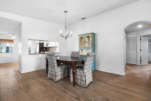 dining area with dark wood-type flooring and ceiling fan with notable chandelier