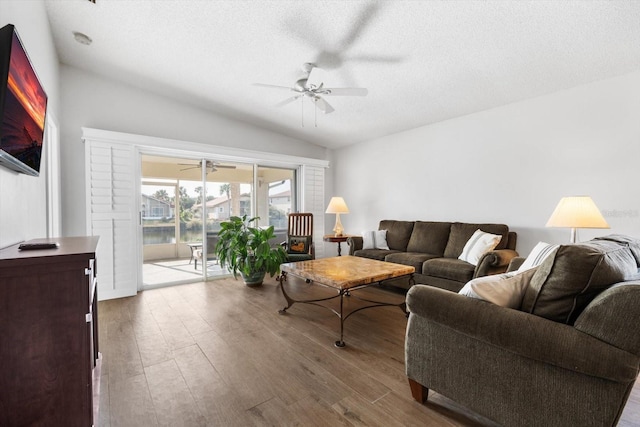 living room featuring vaulted ceiling, a textured ceiling, ceiling fan, and light hardwood / wood-style flooring