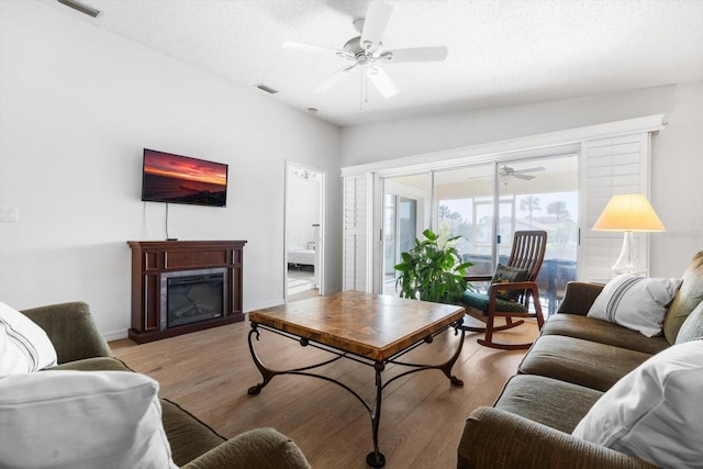 living room with a textured ceiling, light hardwood / wood-style flooring, and ceiling fan