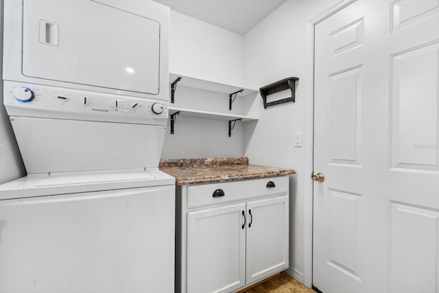 clothes washing area with cabinets and stacked washer and clothes dryer