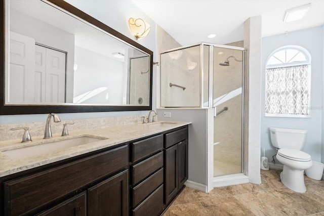 bathroom featuring vanity, a shower with shower door, and toilet