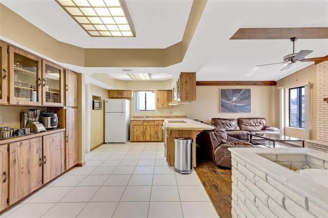 kitchen with a breakfast bar, light tile patterned floors, kitchen peninsula, white fridge, and ceiling fan