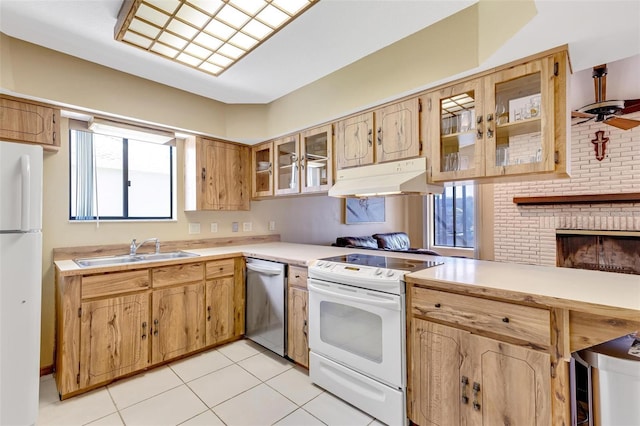 kitchen featuring light tile patterned flooring, sink, ceiling fan, white appliances, and a fireplace