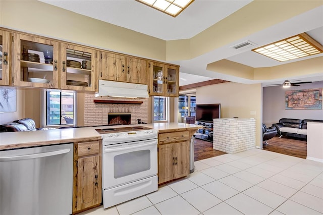 kitchen with light tile patterned floors, stainless steel dishwasher, a tray ceiling, electric stove, and ceiling fan