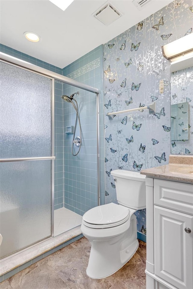 bathroom with a shower with door, vanity, tile patterned floors, and toilet