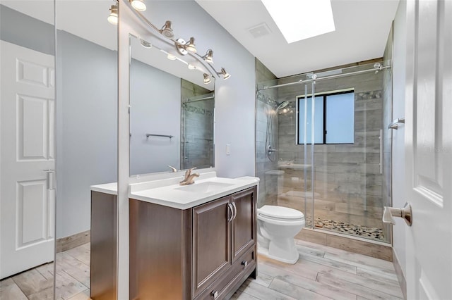 bathroom with a skylight, vanity, toilet, and an enclosed shower