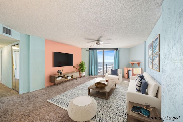 living room with ceiling fan, carpet flooring, and a textured ceiling