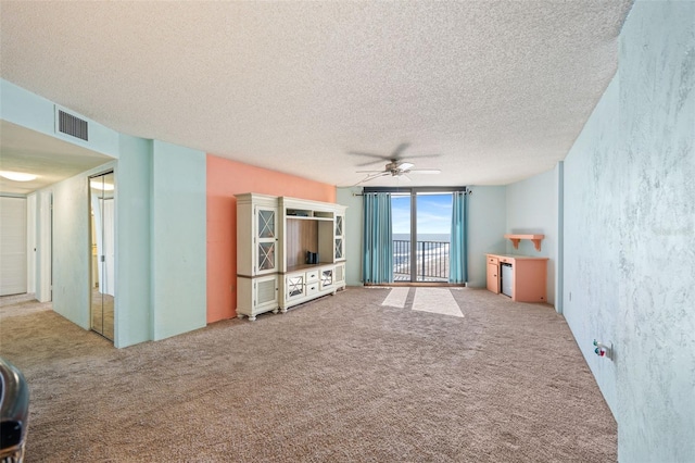 unfurnished living room featuring a textured ceiling, carpet floors, and ceiling fan