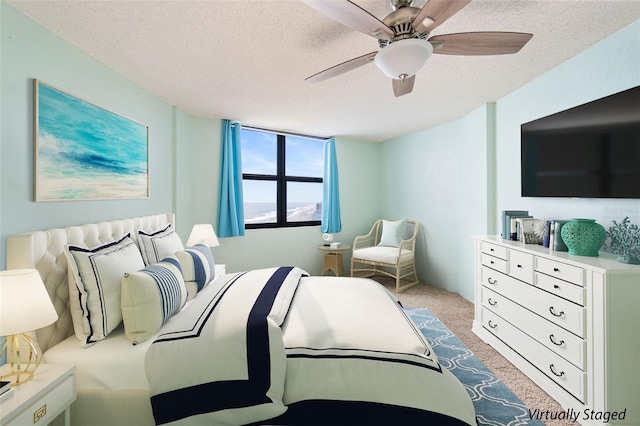 carpeted bedroom with ceiling fan and a textured ceiling