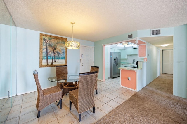 dining room featuring light carpet, sink, and a textured ceiling