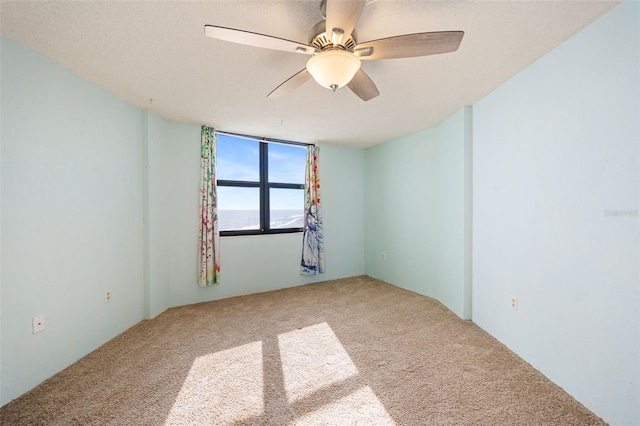 carpeted empty room with ceiling fan and a textured ceiling