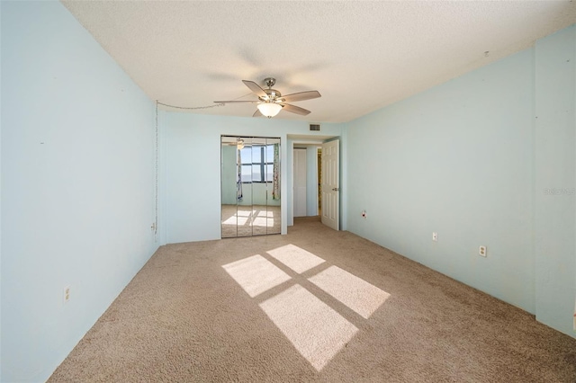 carpeted spare room featuring ceiling fan and a textured ceiling