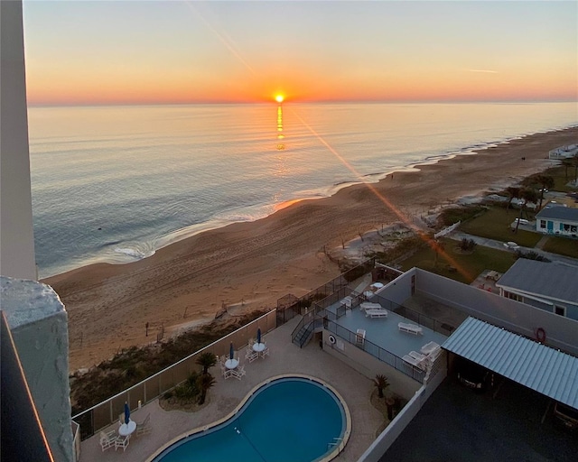 aerial view at dusk with a water view and a view of the beach