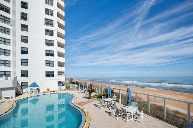 view of pool featuring a view of the beach, a patio area, and a water view