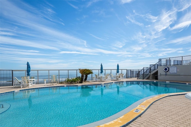 view of swimming pool with a water view and a patio area