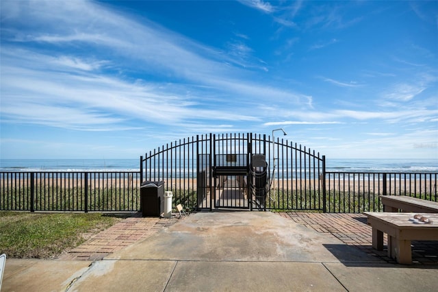 view of gate with a view of the beach and a water view