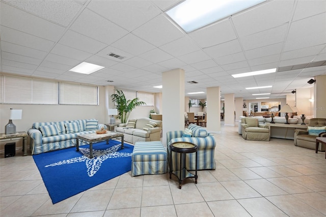 living room featuring a drop ceiling and light tile patterned floors