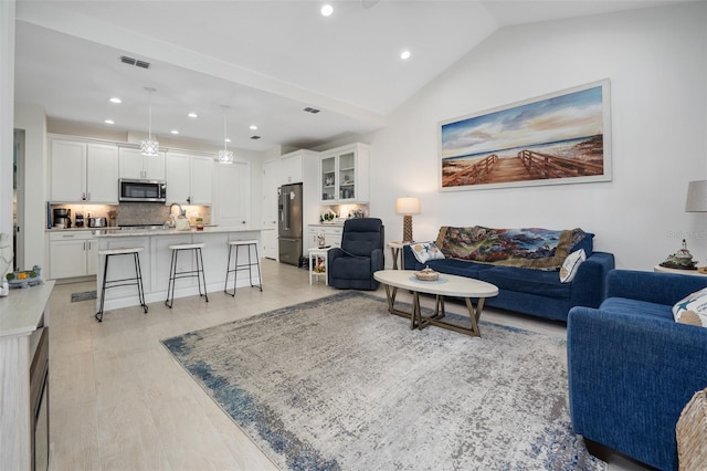 living room featuring lofted ceiling and light hardwood / wood-style floors