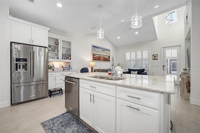 kitchen featuring decorative light fixtures, white cabinetry, lofted ceiling, sink, and stainless steel appliances