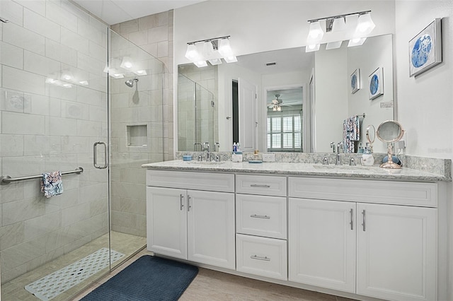 bathroom with a shower with door, vanity, wood-type flooring, and ceiling fan