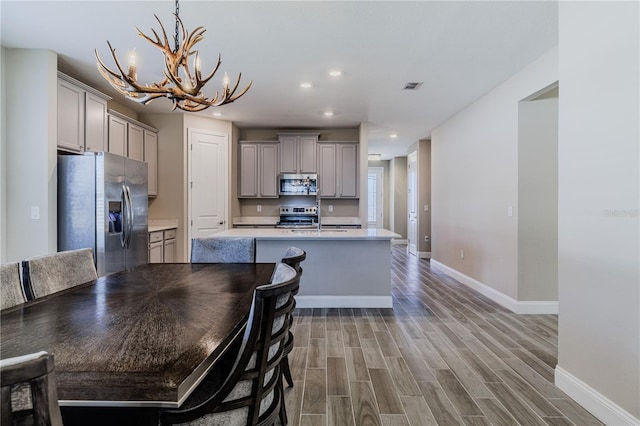 kitchen with stainless steel appliances, light countertops, visible vents, light wood-style flooring, and gray cabinetry