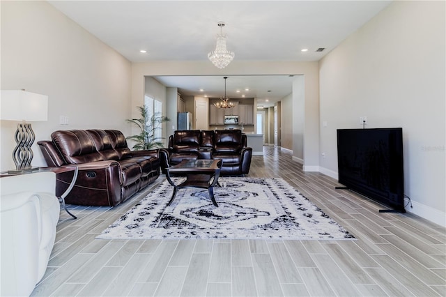 living room featuring baseboards, visible vents, wood finish floors, recessed lighting, and a notable chandelier