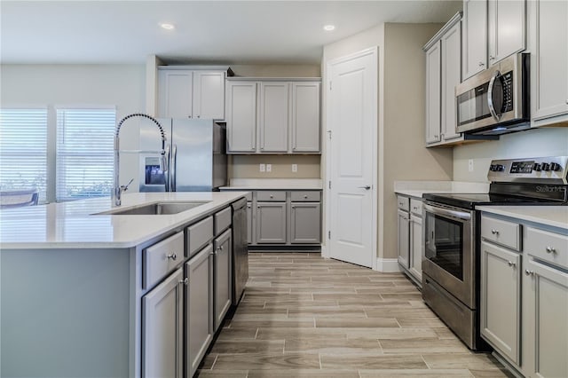 kitchen featuring a sink, wood tiled floor, appliances with stainless steel finishes, and gray cabinetry