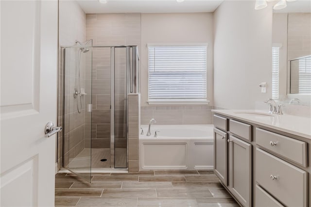 full bath with vanity, a garden tub, a stall shower, and wood finish floors