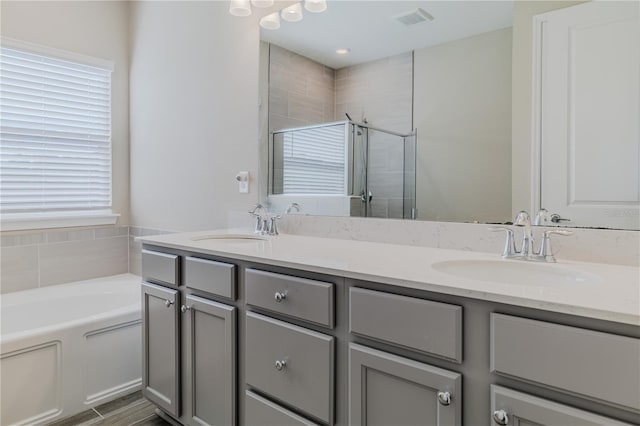 bathroom featuring visible vents, a sink, a shower stall, and double vanity