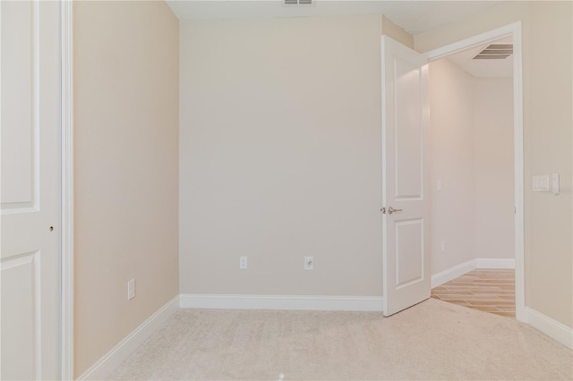 carpeted spare room featuring visible vents and baseboards