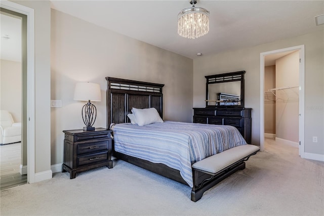 bedroom with an inviting chandelier, a spacious closet, carpet flooring, and baseboards