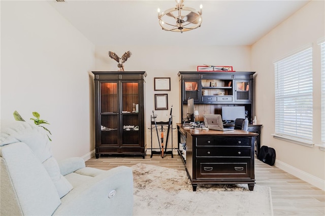 home office with an inviting chandelier, light wood-style floors, and baseboards