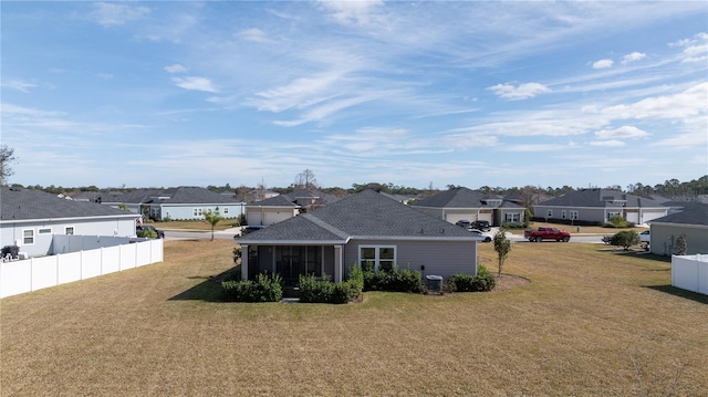 rear view of house featuring a yard, fence, and a residential view