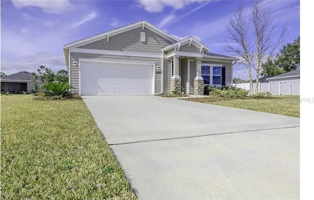 craftsman-style home with an attached garage, concrete driveway, a front yard, and fence