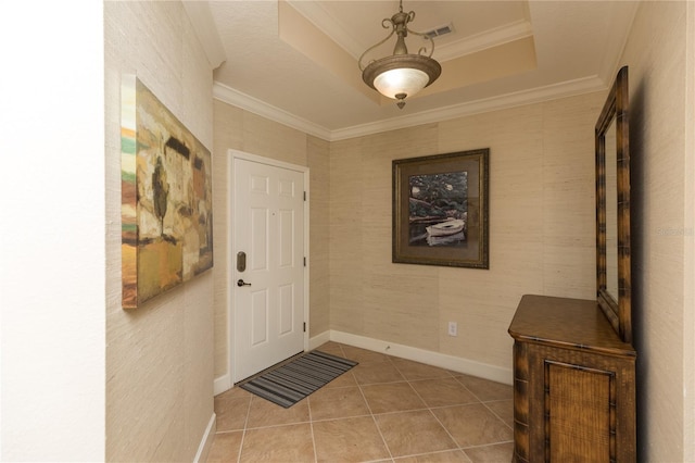 tiled foyer with crown molding and a tray ceiling