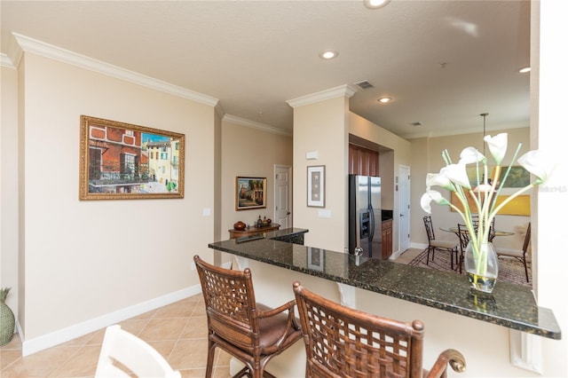 kitchen featuring light tile patterned flooring, ornamental molding, stainless steel fridge, kitchen peninsula, and pendant lighting