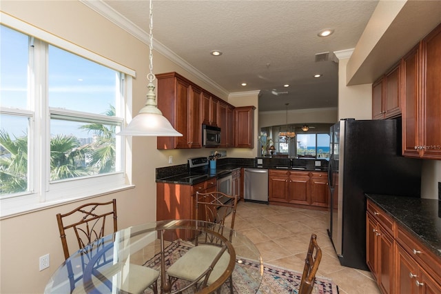 kitchen with light tile patterned floors, crown molding, appliances with stainless steel finishes, hanging light fixtures, and a textured ceiling