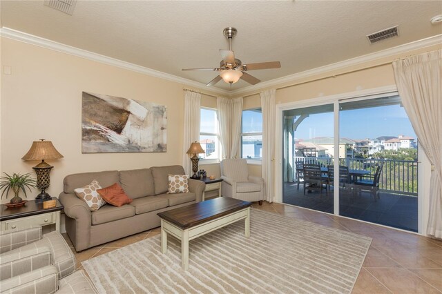 living room with ornamental molding, light tile patterned floors, a textured ceiling, and ceiling fan