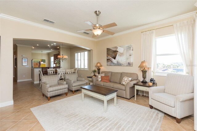 tiled living room featuring ornamental molding, plenty of natural light, and ceiling fan with notable chandelier