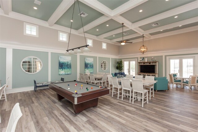 recreation room with hardwood / wood-style floors, a wealth of natural light, and a high ceiling