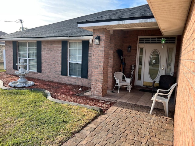 view of exterior entry with a patio area and a lawn