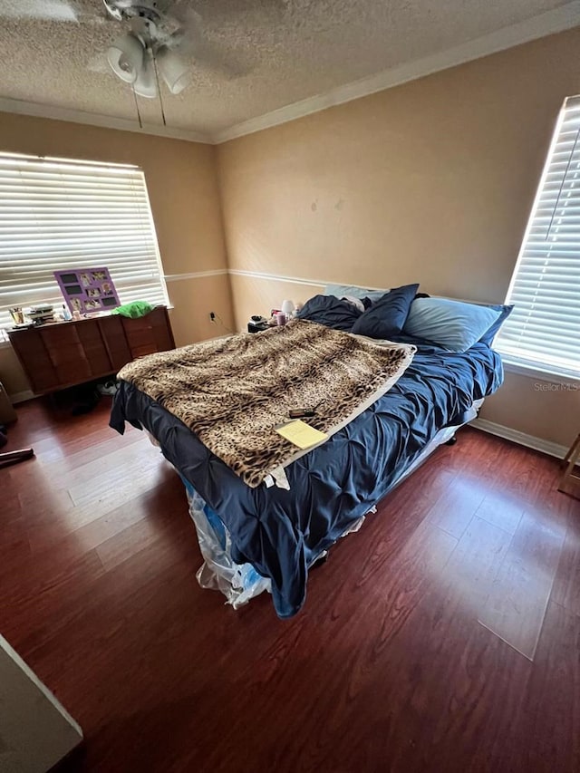 bedroom with ceiling fan, ornamental molding, dark hardwood / wood-style floors, and a textured ceiling