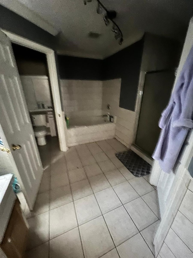 bathroom with track lighting, a bath, tile patterned flooring, and a textured ceiling