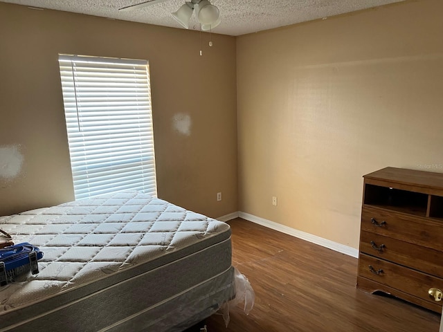 bedroom with ceiling fan, dark hardwood / wood-style flooring, and a textured ceiling