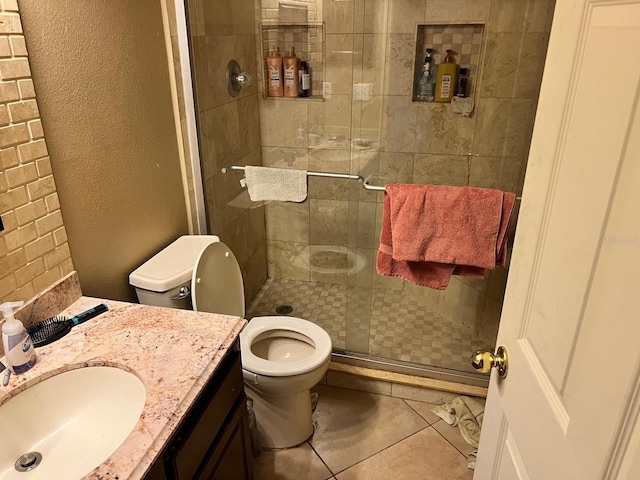 bathroom with vanity, toilet, a shower with shower door, and tile patterned flooring