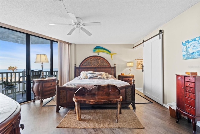 bedroom featuring access to exterior, wood-type flooring, a barn door, and floor to ceiling windows