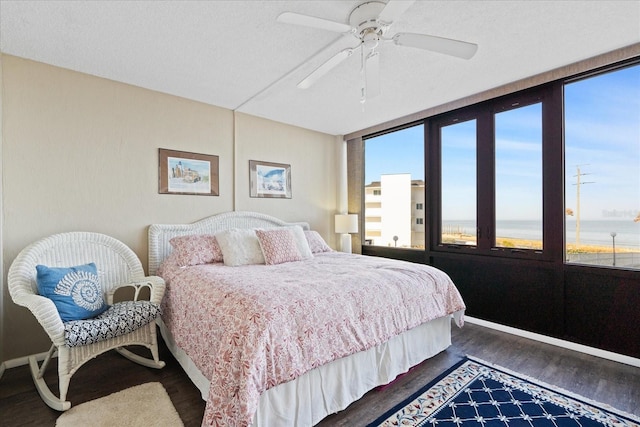 bedroom featuring a textured ceiling, dark wood-type flooring, ceiling fan, and a water view