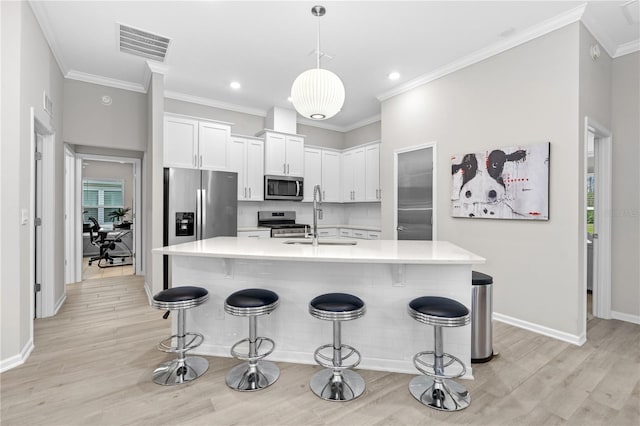 kitchen with a kitchen bar, sink, white cabinetry, pendant lighting, and stainless steel appliances