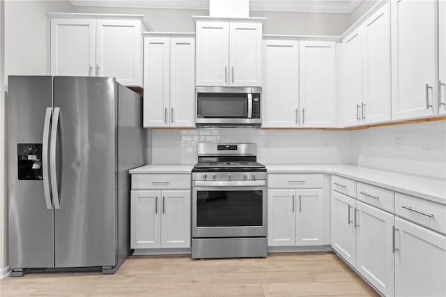 kitchen featuring crown molding, appliances with stainless steel finishes, white cabinetry, tasteful backsplash, and light wood-type flooring