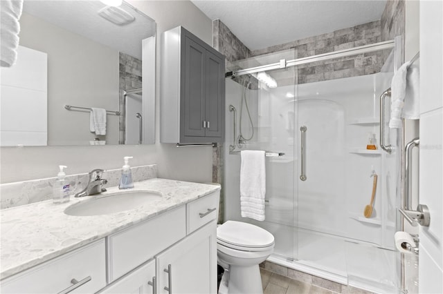 bathroom with a shower with door, vanity, a textured ceiling, and toilet